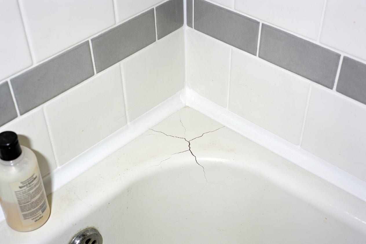 The same bath edge with a fresh white bead of sealant and clean grout